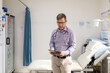 © Austockphoto - Male doctor holding a tablet with a stethoscope around his neck standing in the clinic