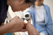 © Austockphoto - Female healthcare worker using a dermatoscope to check female patient's skin on the arms
