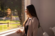 © Austockphoto - Indian woman standing by the window looking outside on a sunny day
