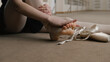 © Framestock - Close up shot of female ballet dancer taking off her pointe shoes after stretching and gymnastic workout in dance studio. Ballerina finished choreography rehearsal. School of classical ballet dance.