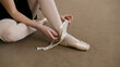 © Framestock - Ballerina in training bodysuit takes off her pointe shoes after stretching and gymnastic workout in dance studio. Female ballet dancer finished preparing for performance. Classic ballet dance school.