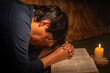 © FABIAN PONCE GARCIA - man praying with his hands on the bible by candlelight on a table