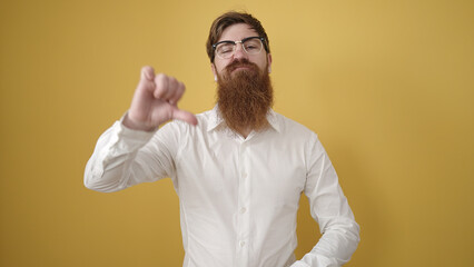 Canvas Print - Young redhead man doing negative gesture with thumb down over isolated yellow background