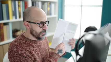 Poster - Young bald man student having video call showing document at university classroom