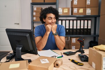 Canvas Print - Hispanic man with curly hair working at small business ecommerce laughing nervous and excited with hands on chin looking to the side