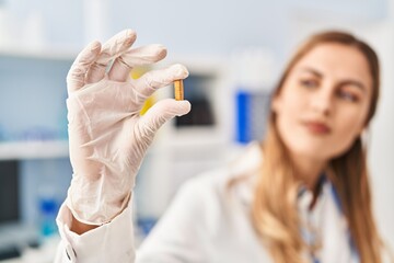 Sticker - Young blonde woman wearing scientist uniform holding pill at laboratory