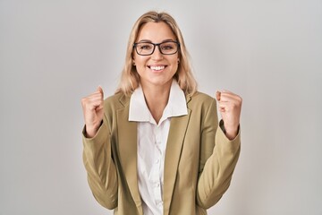 Sticker - Young caucasian woman wearing glasses screaming proud, celebrating victory and success very excited with raised arms