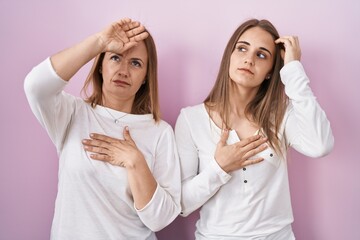 Poster - Middle age mother and young daughter standing over pink background touching forehead for illness and fever, flu and cold, virus sick