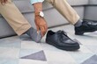 © Krakenimages.com - Senior grey-haired man suffering for feet pain sitting on sofa at home