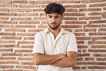 Poster - Arab man with beard standing over bricks wall background skeptic and nervous, disapproving expression on face with crossed arms. negative person.