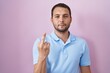 © Krakenimages.com - Hispanic man standing over pink background showing middle finger, impolite and rude fuck off expression