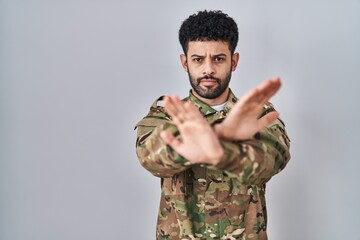 Sticker - Arab man wearing camouflage army uniform rejection expression crossing arms and palms doing negative sign, angry face