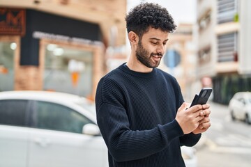 Canvas Print - Young arab man smiling confident using smartphone at street