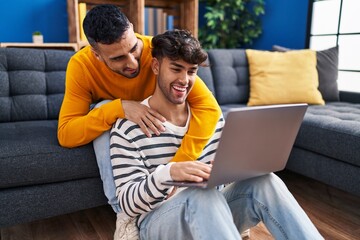 Canvas Print - Two man couple using laptop sitting on sofa at home