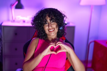 Poster - Young middle eastern woman streamer smiling confident doing heart symbol with hands at gaming room