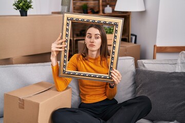 Poster - Young caucasian woman at new home holding empty frame depressed and worry for distress, crying angry and afraid. sad expression.