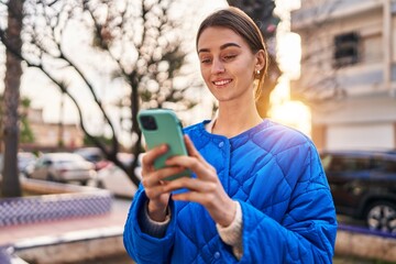 Wall Mural - Young caucasian woman smiling confident using smartphone at street