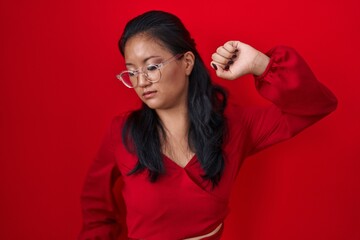 Poster - Asian young woman standing over red background stretching back, tired and relaxed, sleepy and yawning for early morning