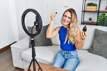 Wall Mural - Young woman recording skin care tutorial by smartphone at home