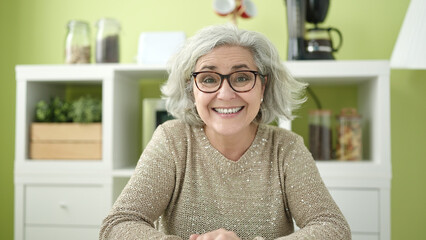 Canvas Print - Middle age woman with grey hair smiling confident sitting on table at home