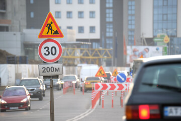 Wall Mural - Roadworks warning traffic signs of construction work on city street and slowly moving cars