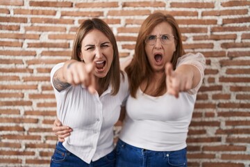 Canvas Print - Hispanic mother and daughter wearing casual white t shirt pointing displeased and frustrated to the camera, angry and furious with you