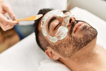 Canvas Print - Young hispanic man having facial mask treatment at beauty center