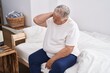 © Krakenimages.com - Middle age grey-haired man suffering for neck injury sitting on bed at bedroom