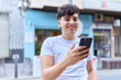 © Krakenimages.com - Non binary man smiling confident using smartphone at street