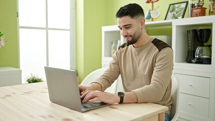Canvas Print - Young arab man using laptop sitting on table at home