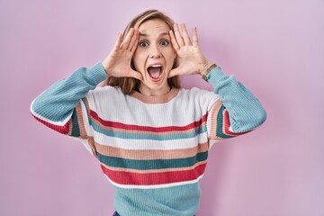 Sticker - Young blonde woman standing over pink background smiling cheerful playing peek a boo with hands showing face. surprised and exited