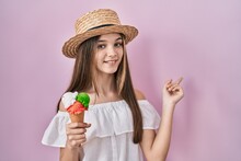 Teenager Girl Holding Ice Cream With A Big Smile On Face, Pointing With Hand Finger To The Side Looking At The Camera.
