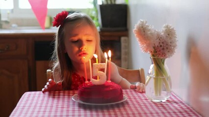 Wall Mural - Happy little girl celebrating her fifth birthday and making a wish. Little kid with birthday cake and candle