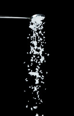 Wall Mural - Salt fall, crystal white grain peanuts explode abstract cloud fly from silver spoon. Beautiful complete seed salt, food object design. Selective focus freeze shot black background isolated