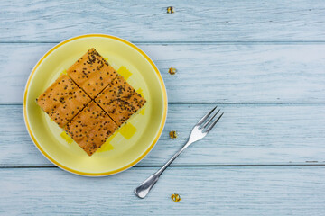 Top view, square cut of homemade sweet and solf perilla seeds cake on a round yellow plate. Delicious and healthy bakery.