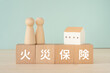 © ELUTAS - 火災保険と書かれたブロックと人形と家