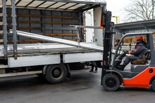 Forklift Loader In The Metal Warehouse. Loading And Unloading Stainless Metal Pipes