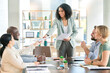© Lune V A/peopleimages.com - Black woman, leader with business people and team in meeting, paperwork and presentation with collaboration. Diversity, teamwork and project proposal with speaker, happy group in conference room