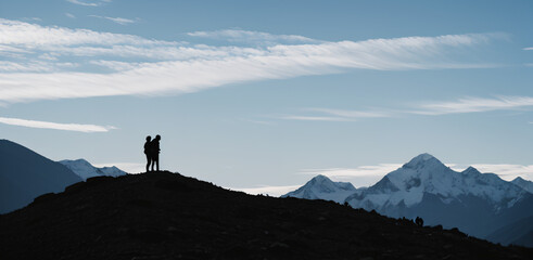 Silhouette of two person on top of mountain peak. / Holding Hands / coaching goal, success and teamwork concepts - Mountains Mountaineer / Space for Text / Blank Space / Copy Text