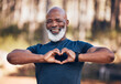 © Mumtaaz D/peopleimages.com - Black man, fitness and heart portrait for exercise, fitness and health while outdoor with a smile. Healthy senior person in nature forest happy with hand emoji sign for workout and cardio training