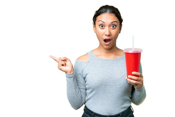 Wall Mural - Young Uruguayan woman holding soda over isolated chroma key background surprised and pointing side