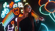 © alones - Stylish beautiful surprised woman with vintage glasses in a fashion black top on a dark background with bright neon lights objects. Urban trendy woman