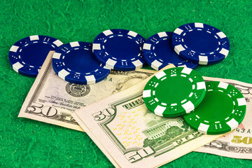 Five blue chips and two green chips lie on two fifty dollar bills