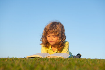 Aufkleber - Boy child reading book, lying down on green grass. Kids adventure, freedom and carefree children.