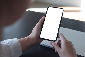 Wall Mural - Mockup, blank screen cell phone. women hand holding, using mobile phone, working on laptop computer at  office. white empty space for advertisement. contact business, web template or mobile app design