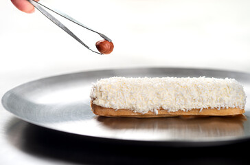 French eclair with coconut crumble hazelnut on a plate .Eclair making