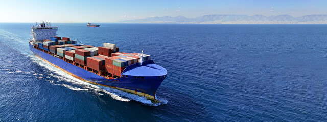 Wall Mural - Aerial drone ultra wide panoramic photo of container tanker ship carrying truck size colourful containers in deep blue open ocean sea