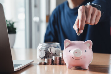 Wall Mural - Hand putting coins in a piggy bank for save money and Saving Money concept.