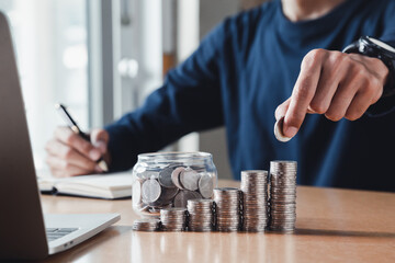 Wall Mural - Man hand holding coin on wood table. Save money and financial investment and saving money for buying house, financial plan home loan concept.