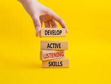 Listening Skills Symbol. Concept Word Develop Active Listening Skills On Wooden Blocks. Beautiful Yellow Background. Businessman Hand. Business And Develop Active Listening Skills Concept. Copy Space